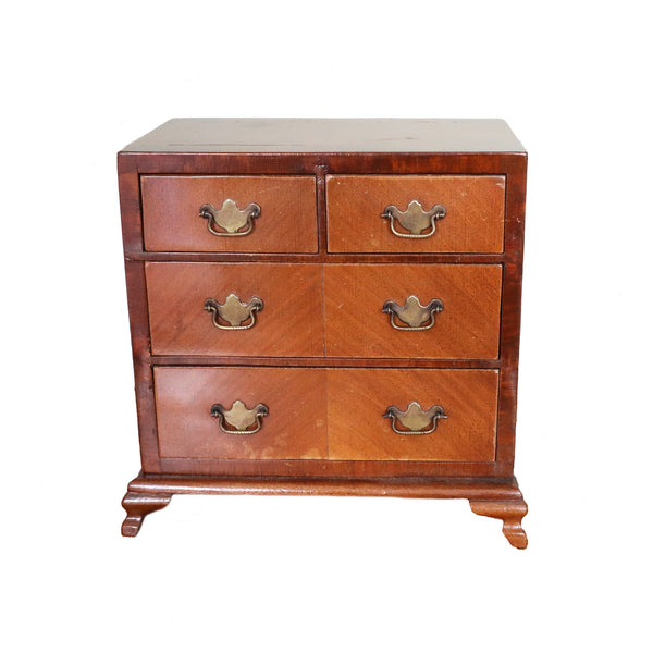 Wooden dresser with four drawers and brass handles on a white background