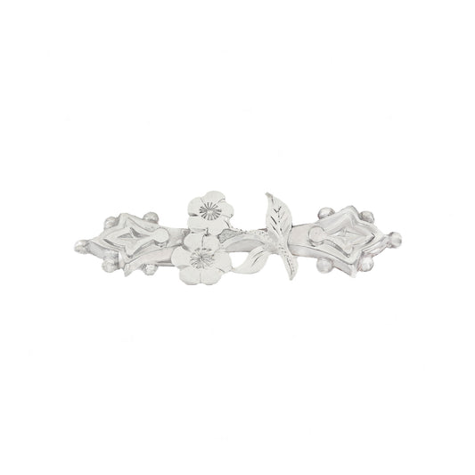 Silver brooch with floral design on a white background