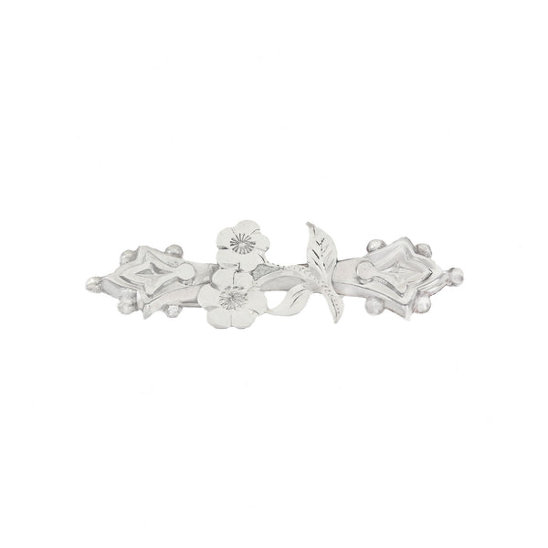Silver brooch with floral design on a white background