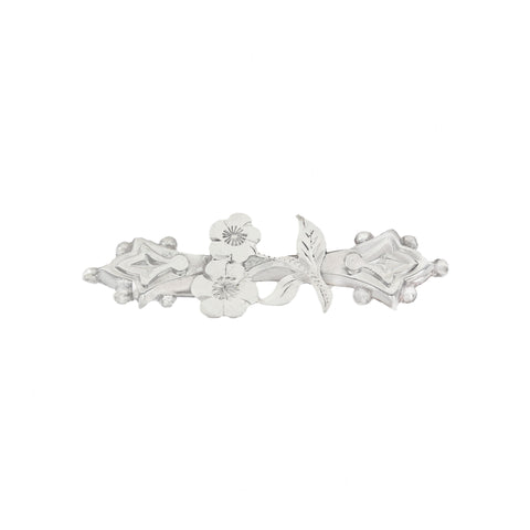 Silver brooch with floral design on a white background