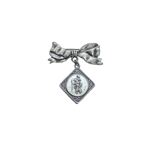 Silver brooch with bow and pendant on a white background