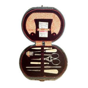antique sewing kit with tools in an ornate case on a white background