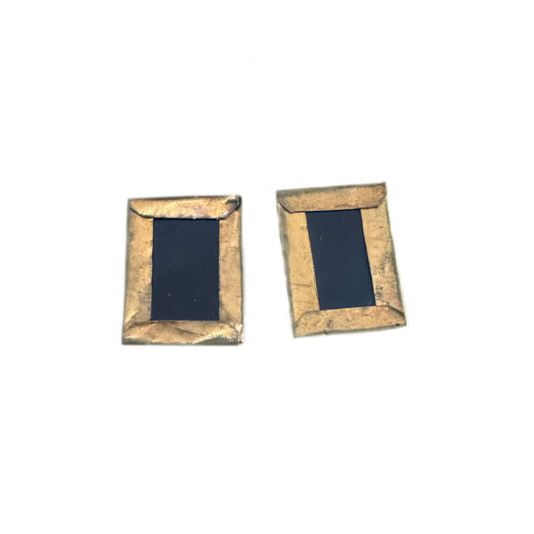 Two rectangular black objects with gold frames on a white background