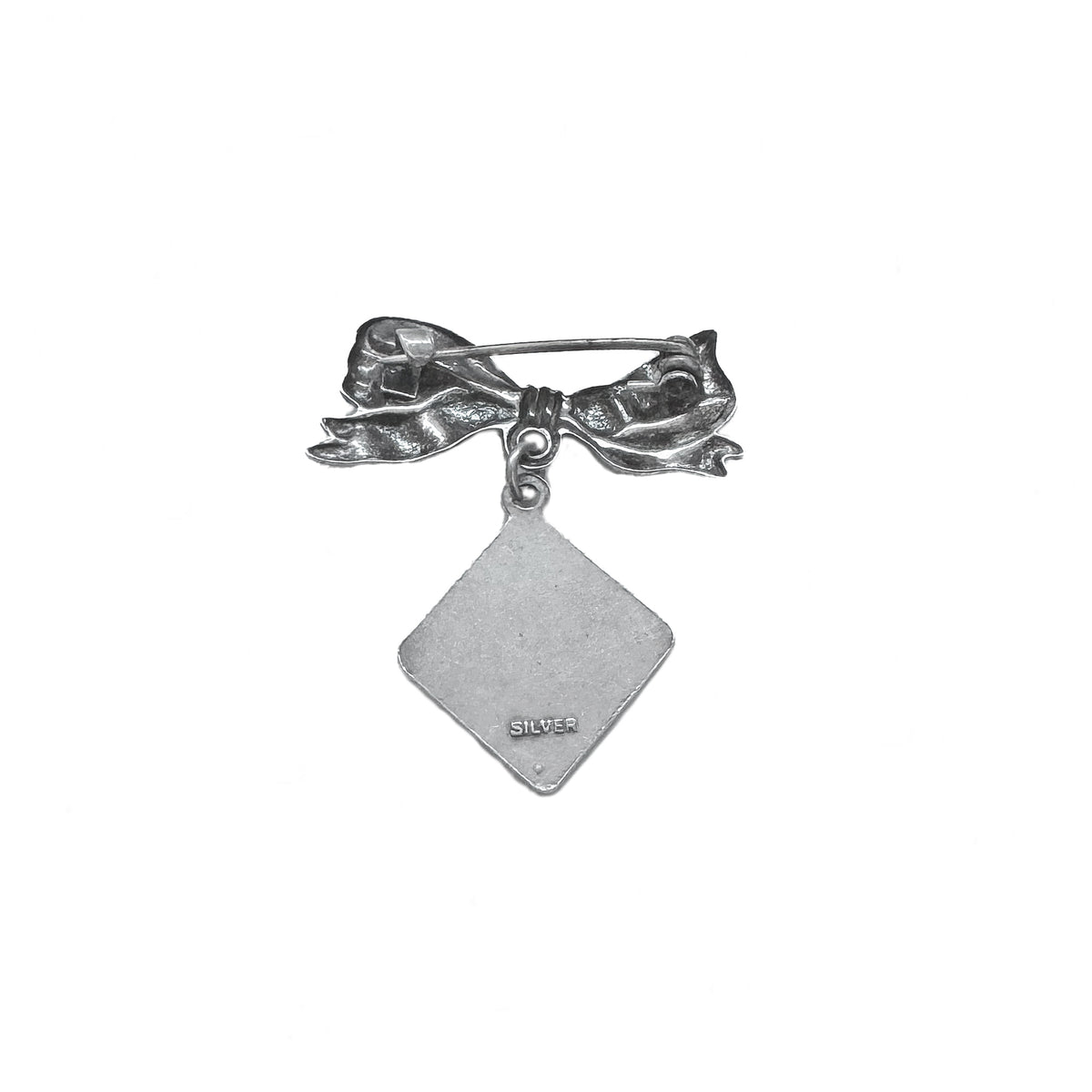 Silver bow-shaped brooch with a diamond-shaped pendant on a white background