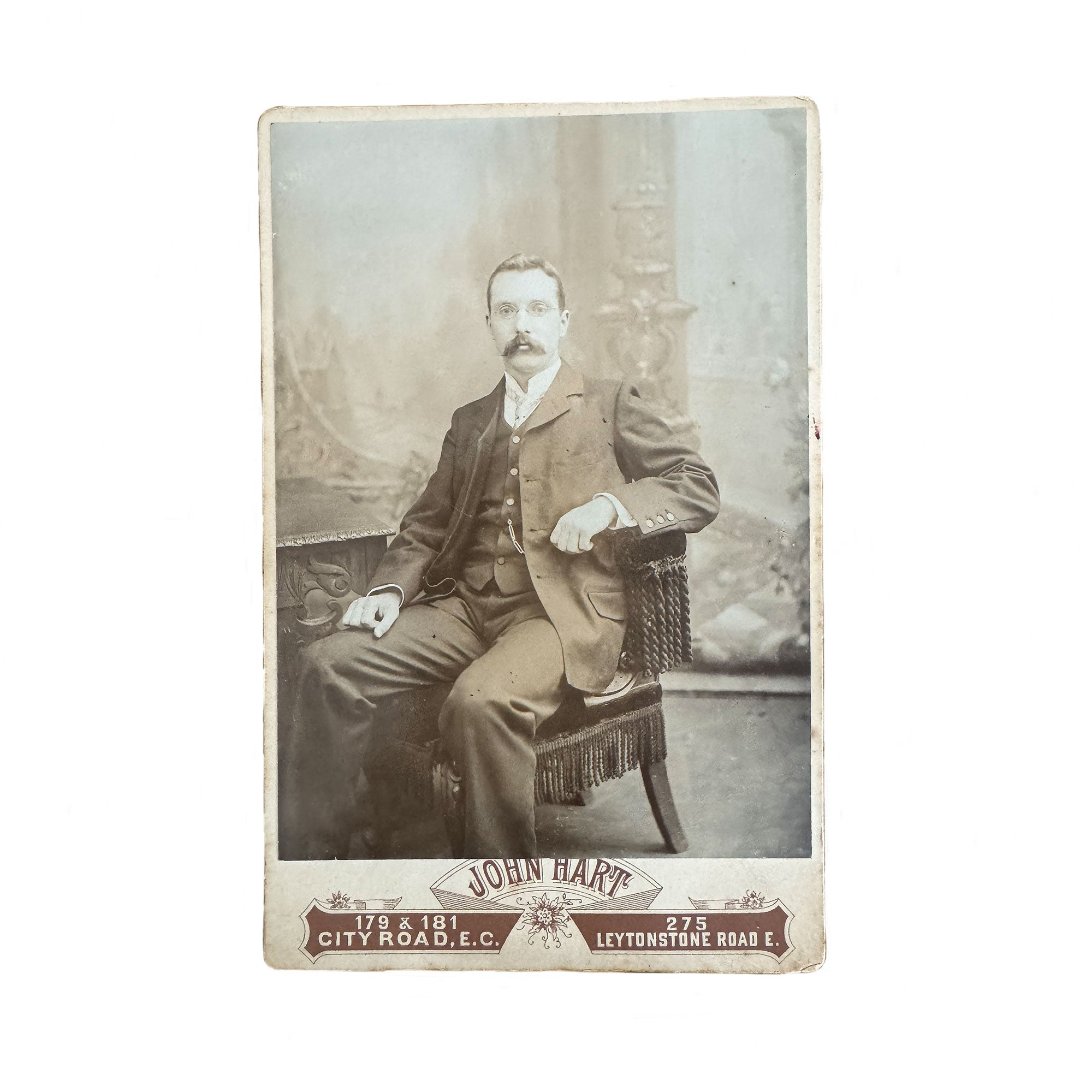 Antique photograph of a man in formal attire sitting on a chair, with 'John Hart' studio information at the bottom.