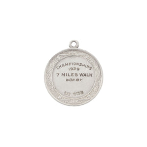 Silver medal with engraved text on a white background