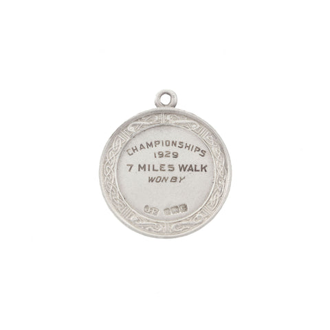 Silver medal with engraved text on a white background