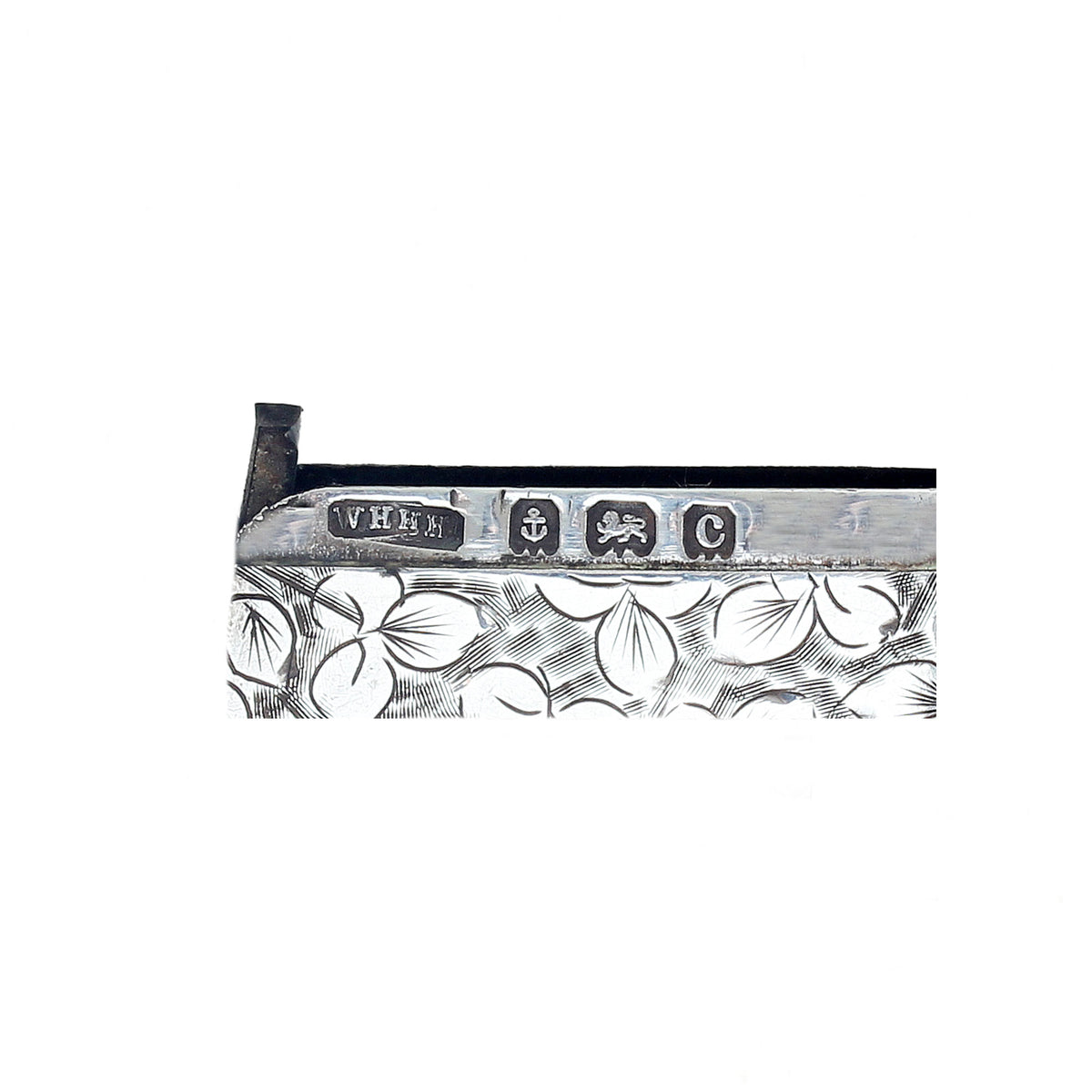 Close-up of a silver object with engraved design and visible hallmarks on a white background