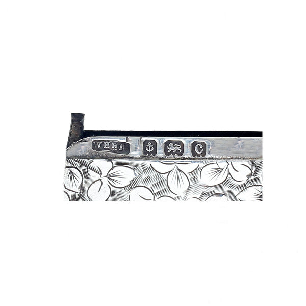 Close-up of a silver object with engraved design and visible hallmarks on a white background