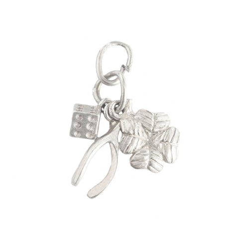 Silver charm with a leaf, dice and wishbone on a white background