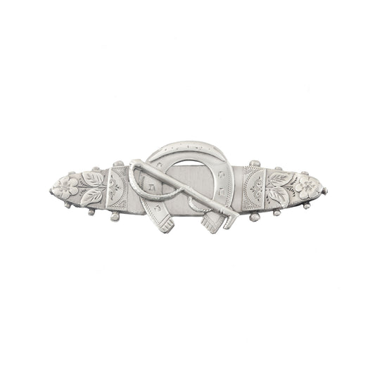Decorative silver brooch with floral and horseshoe designs on a white background