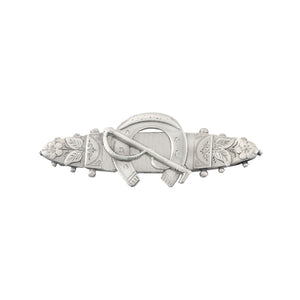 Decorative silver brooch with floral and horseshoe designs on a white background