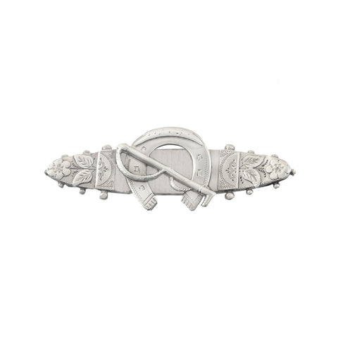 Decorative silver brooch with floral and horseshoe designs on a white background