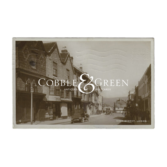 Vintage postcard depicting the High Street in Lewes, East Sussex, with a black and white photograph of shops and buildings.
