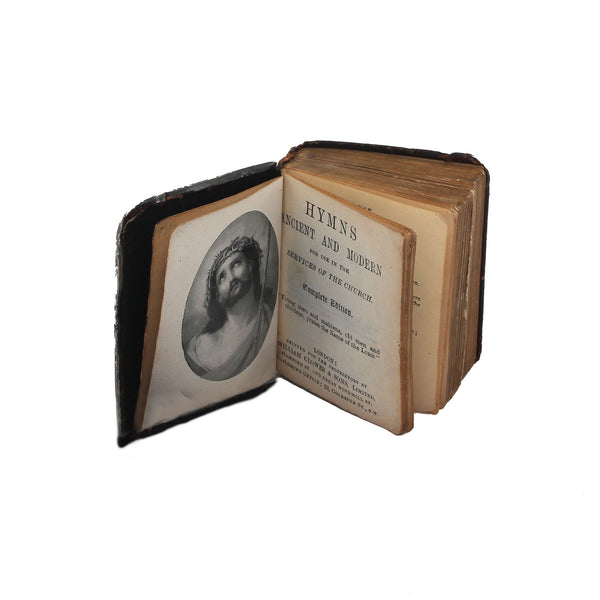 Open vintage book titled 'Hymns Ancient and Modern' with a portrait on the left page.