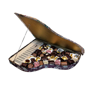Piano-shaped box filled with assorted chocolates on a white background