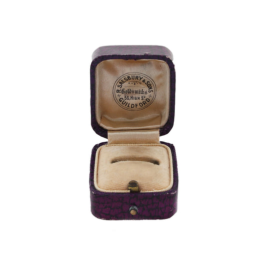 Open purple jewelry box with beige interior, featuring a brand logo on a white background