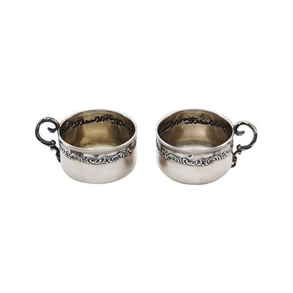 Two silver cups with ornate handles on a white background