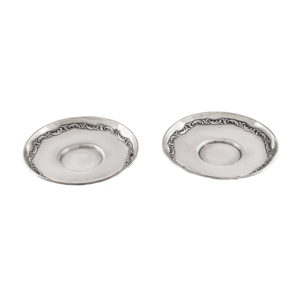 Two silver ornate saucers on a white background