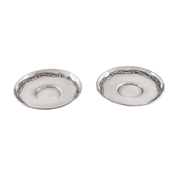 Two silver ornate saucers on a white background