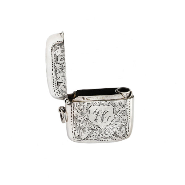 Silver vesta with intricate designs and monogram on a white background