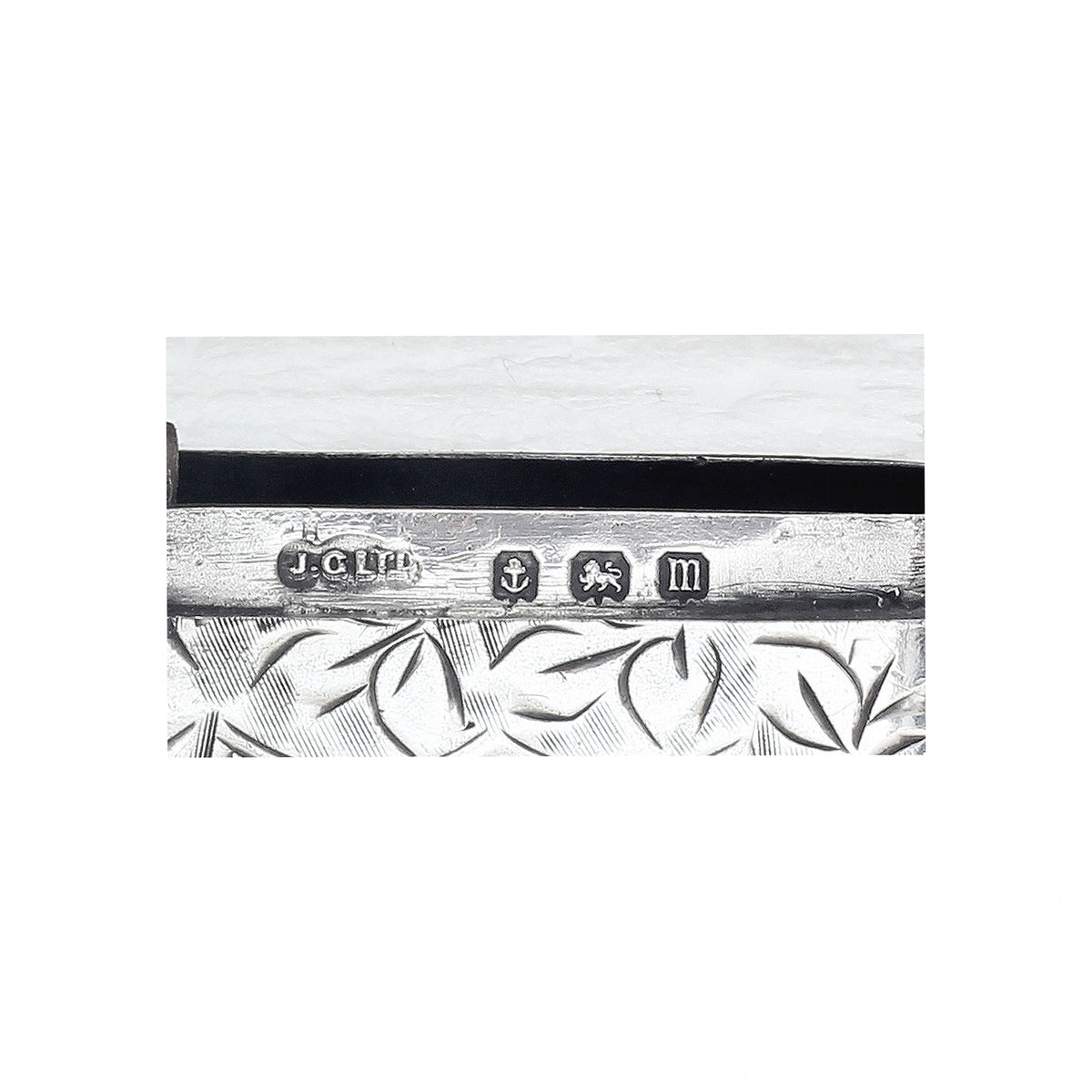 Decorative silver object with engraved design on a white background