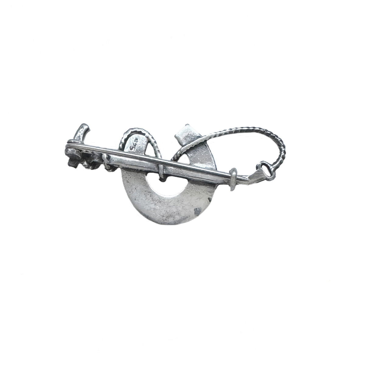 Silver brooch with a circular design on a white background