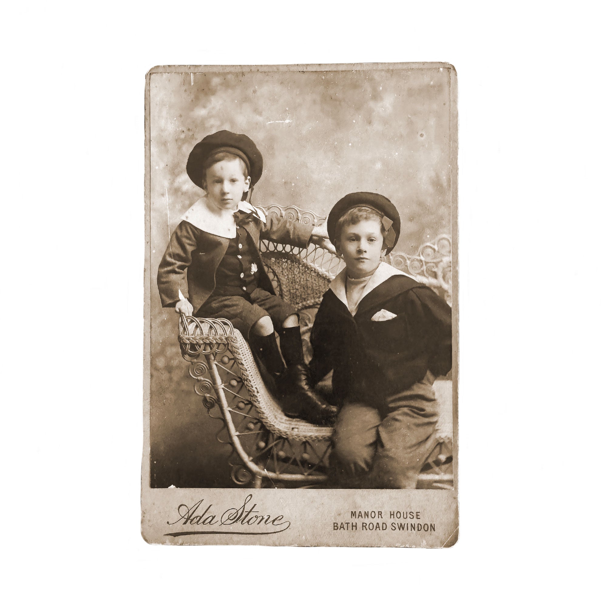 Vintage photograph of two boys in formal attire sitting on a decorative bench.