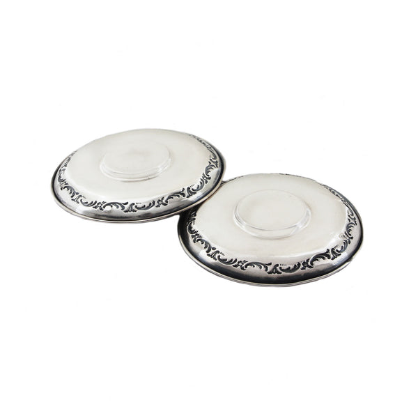 Two white saucers with silver decorative rims on a white background