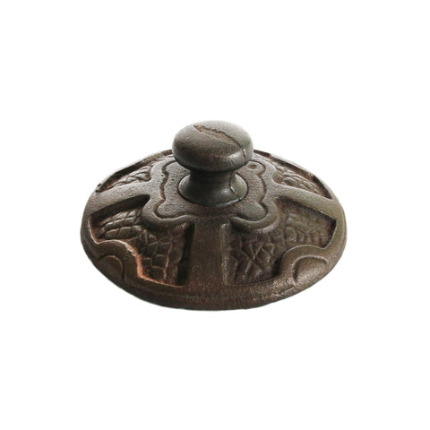 An old cast iron detailed heavy paperweight with green felt underneath and the letters 'SO' on the top edge.