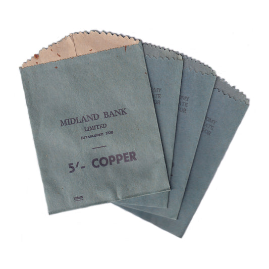 A collection of four gray paper coin envelope bags with the text 'MIDLAND BANK LIMITED' and '5/- COPPER' printed on them, indicating they are for 5 shillings in copper.
