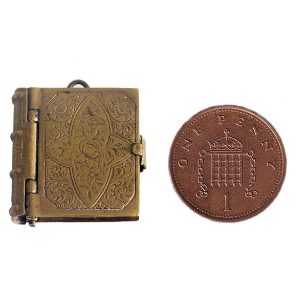 miniature brass photo album cover next to a penny coin