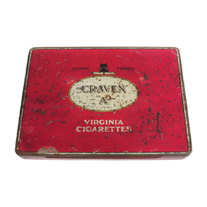 A vintage red Craven A Virginia cigarette tin with branding and text, showing signs of wear and use.