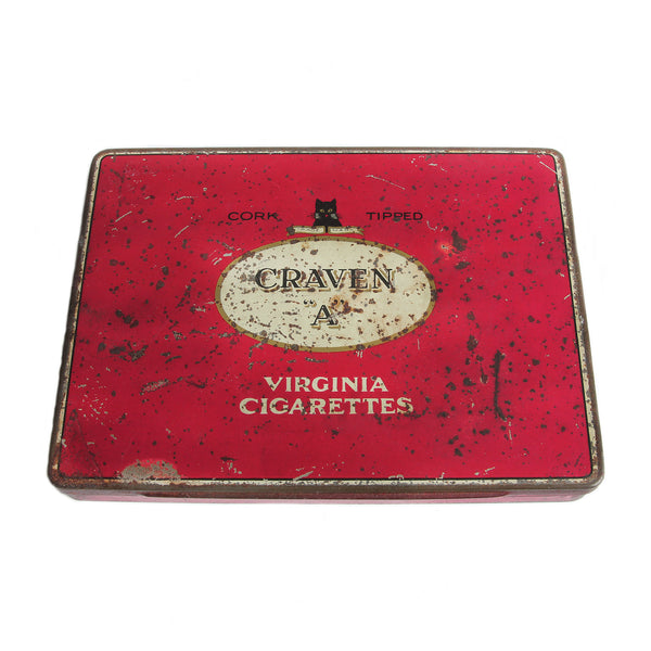 A vintage red Craven A Virginia cigarette tin with branding and text, showing signs of wear and use.
