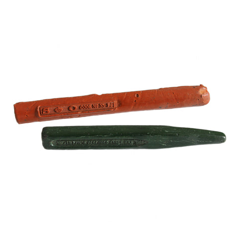 Two antique wax sealing sticks in orange and green, with visible writing and markings.
