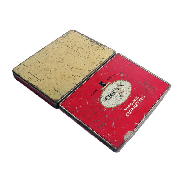 An empty metal tin Craven A red and black and cream scratched on the outside