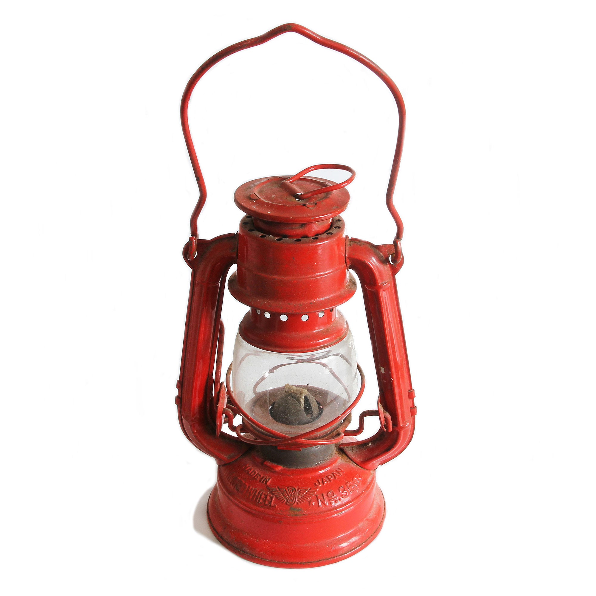 A vintage red oil lantern with a clear glass window and two top handles, labeled as 'Winged Wheel No. 350', indicating it is a 1960s model made in Japan.