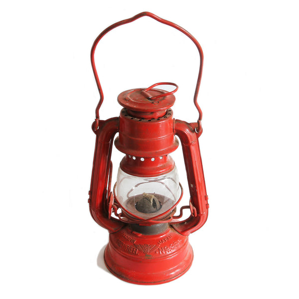 A vintage red oil lantern with a clear glass window and two top handles, labeled as 'Winged Wheel No. 350', indicating it is a 1960s model made in Japan.