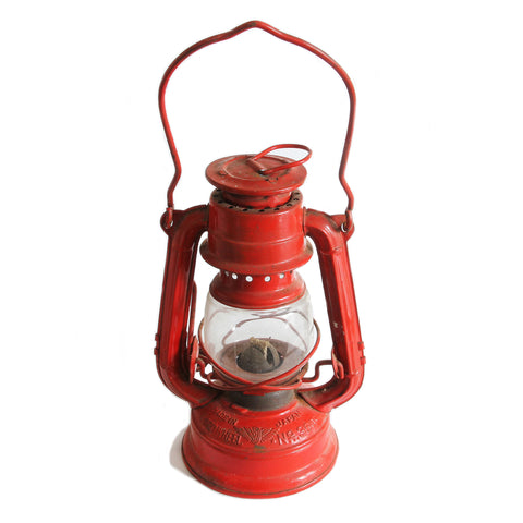 A vintage red oil lantern with a clear glass window and two top handles, labeled as 'Winged Wheel No. 350', indicating it is a 1960s model made in Japan.